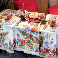 Tovaglia natalizia Schiaccianoci in puro lino di Tessitura Toscana Telerie. Fantasia piazzata su fondo chiaro, con abeti addobbati, regali e giocattoli che richiamano l'atmosfera del Natale. Misura rettangolare 170x270 cm.