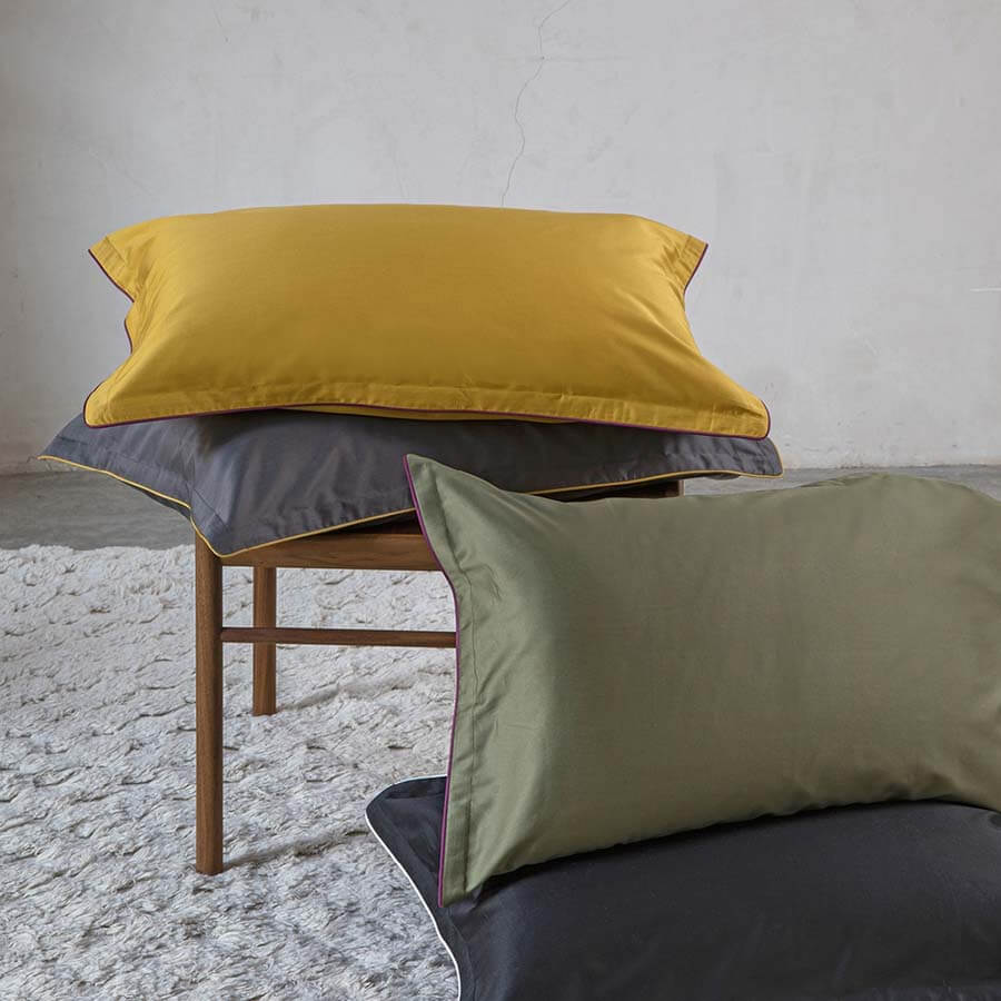 Completo lenzuola matrimoniale Fazzini Deal, in raso di puro cotone tinta unita. Dettaglio federe ocra, grigio e verde.