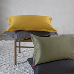 Completo lenzuola matrimoniale Fazzini Deal, in raso di puro cotone tinta unita. Dettaglio federe ocra, grigio e verde.