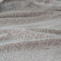 Copriletto estivo matrimoniale Leslie di Blumarine, in elegante raso jacquard. Romantica fantasia jacquard con linee sinuose che si intrecciano a formare delle rose, colore beige/tortora, con logo Blumarine in preziosi cristalli Swarovski. Coperta estiva