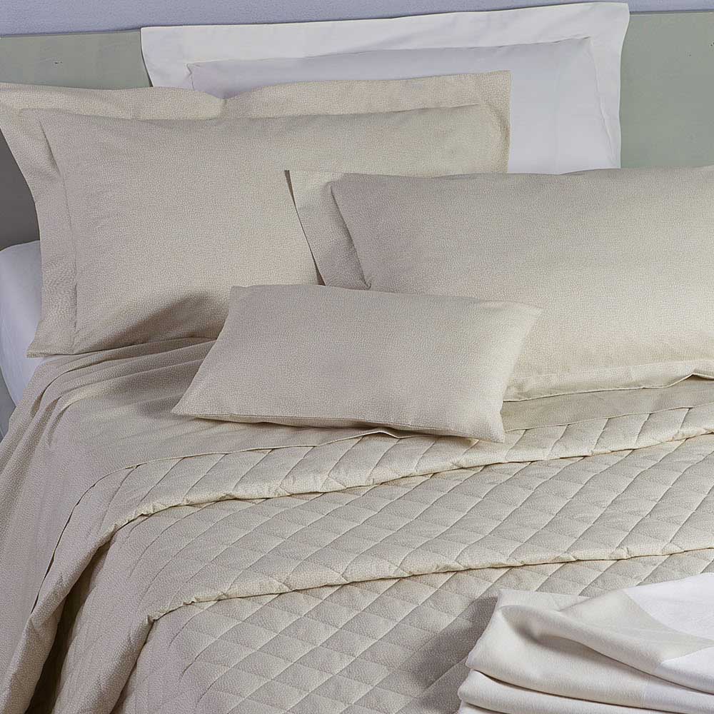 Completo lenzuola matrimoniale Borbonese Oplà in percalle di puro cotone. Variante di colore ecrù (beige). Completo lenzuola Borbonese con stampa a occhio di pernice che si sviluppa sulle federe e sul lenzuolo di sopra. Il lenzuolo di sotto con gli angoli è invece in percalle tinta unita.