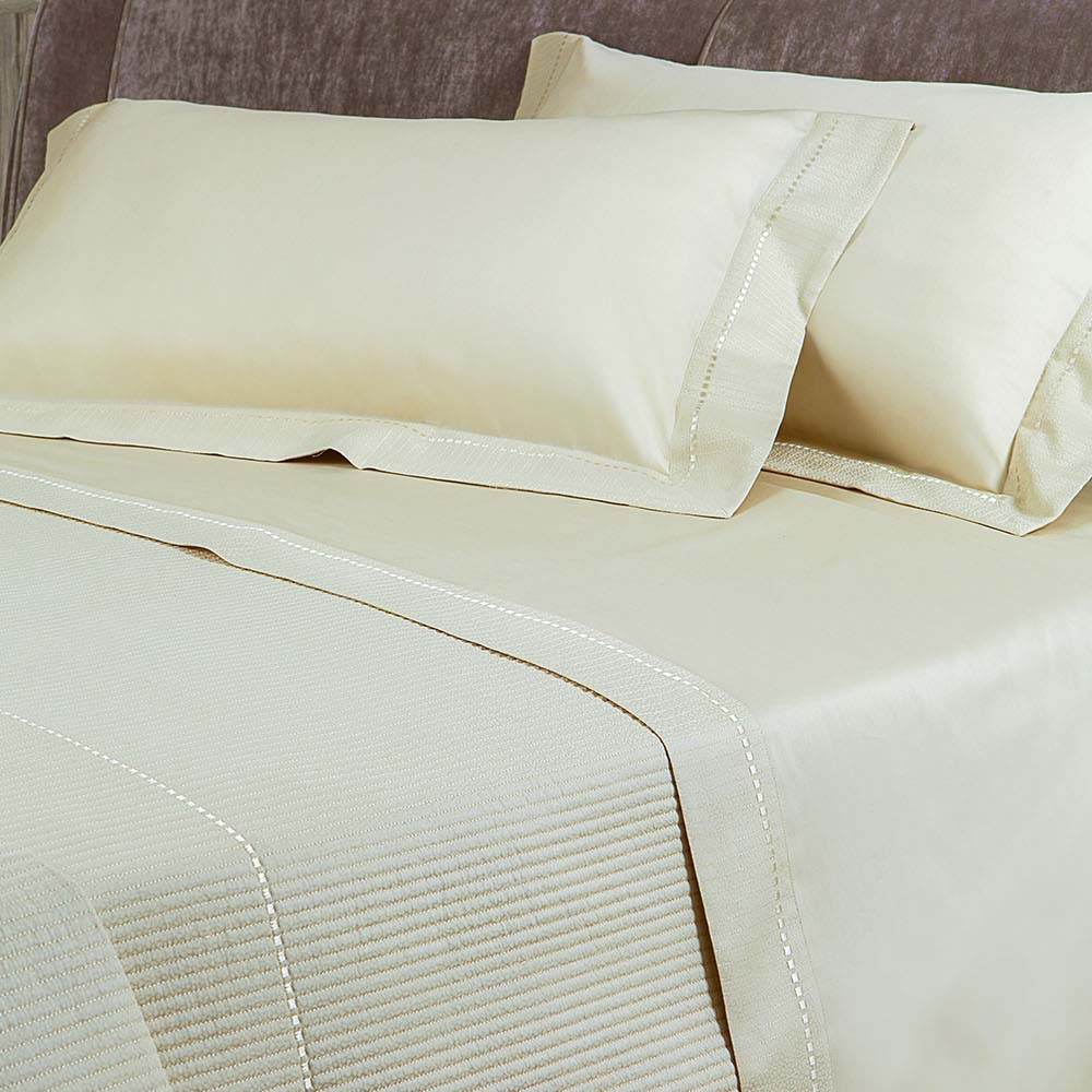 Completo lenzuola matrimoniale Borbonese New York in raso di puro cotone 300 T.C.. Variante di colore sabbia. Il completo lenzuola Borbonese New York è confezionato con lista ricamata sulla balza del lenzuolo di sopra e sui volant delle federe. Ha un look sobrio ma elegante ed è impreziosito da placchetta di metallo con logo Borbonese.