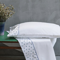 Completo lenzuola matrimoniale Fazzini Spring in raso e percalle di puro cotone. Tinta unita bianco e blu/carta da zucchero con balza bianca con roselline ricamate. Collezione primavera estate 2022