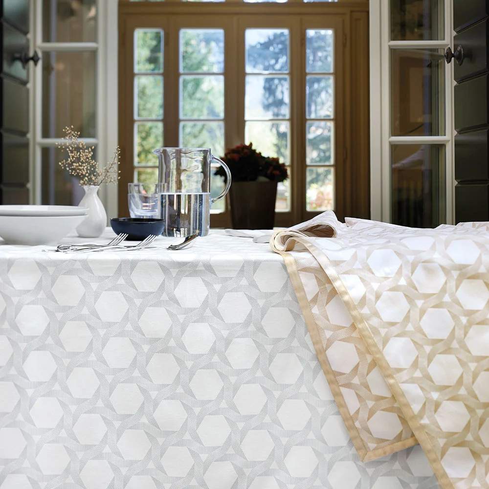 Tovaglia natalizia Gabel Charme in panama di puro cotone. La fantasia geometrica è stampata con pigmento ad effetto metallizzato. La tovaglia è inoltre rifinita con nastro lamè applicato ai bordi. Fantasia geometrica in due varianti di colore: champagne (dorata) e perla (argentata). Disponibile nella misura rettangolare x12: 150x270 cm.