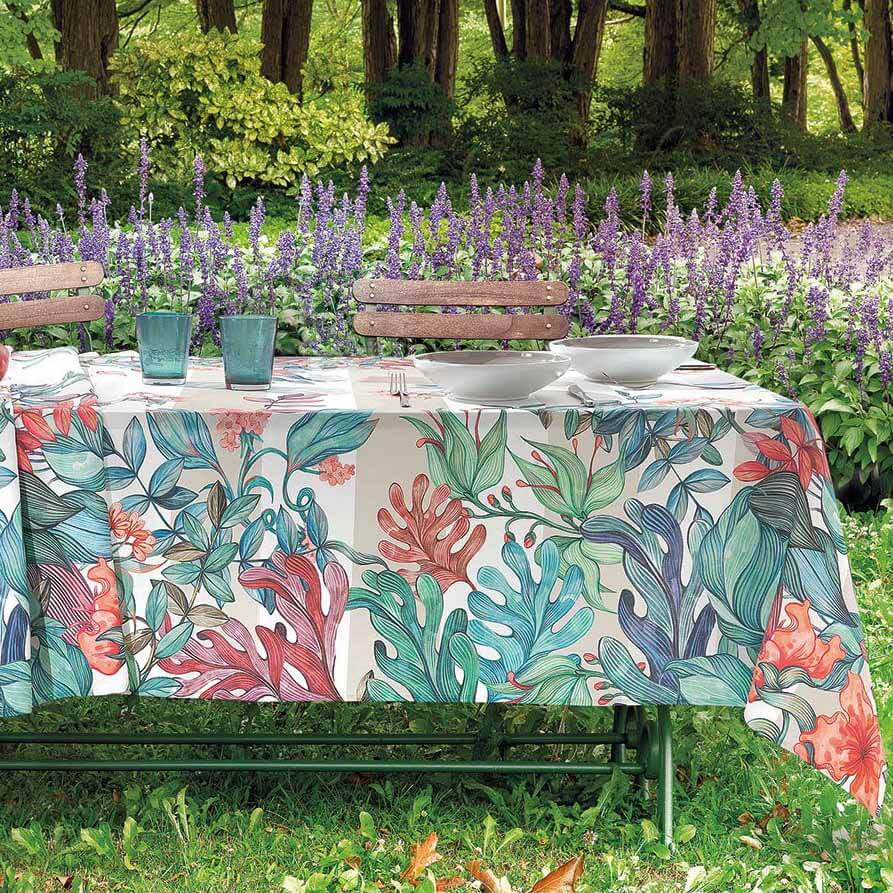 Tovaglia Gabel Eden in panama di puro cotone con stampa digitale. Fantasia con fiori e foglie dai colori arancio e verde acqua su fondo chiaro.
