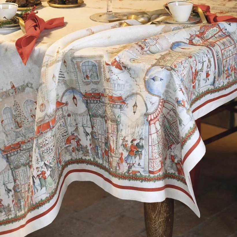 Tovaglia natalizia Christmas Shopping in puro lino di Tessitura Toscana Telerie. Fantasia su fondo chiaro, con scene di shopping natalizio originali e piene di dettagli. Queste scene fanno respirare aria di festa e richiamano vari elementi tipici del Natale, come gli abeti addobbati, Babbo Natale, i negozi illuminati e le ghirlande. Misura rettangolare x12 (170x270 cm). Dettaglio fantasia.