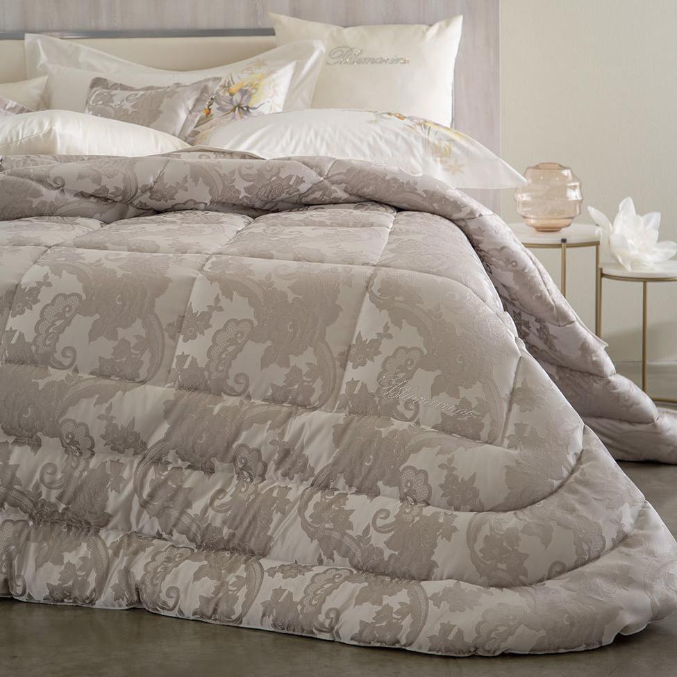 Trapunta Invernale matrimoniale Annarosa di Blumarine, in elegante raso jacquard. Fantasia jacquard a tema floreale colore tortora, con logo Blumarine in preziosi cristalli Swarovski.