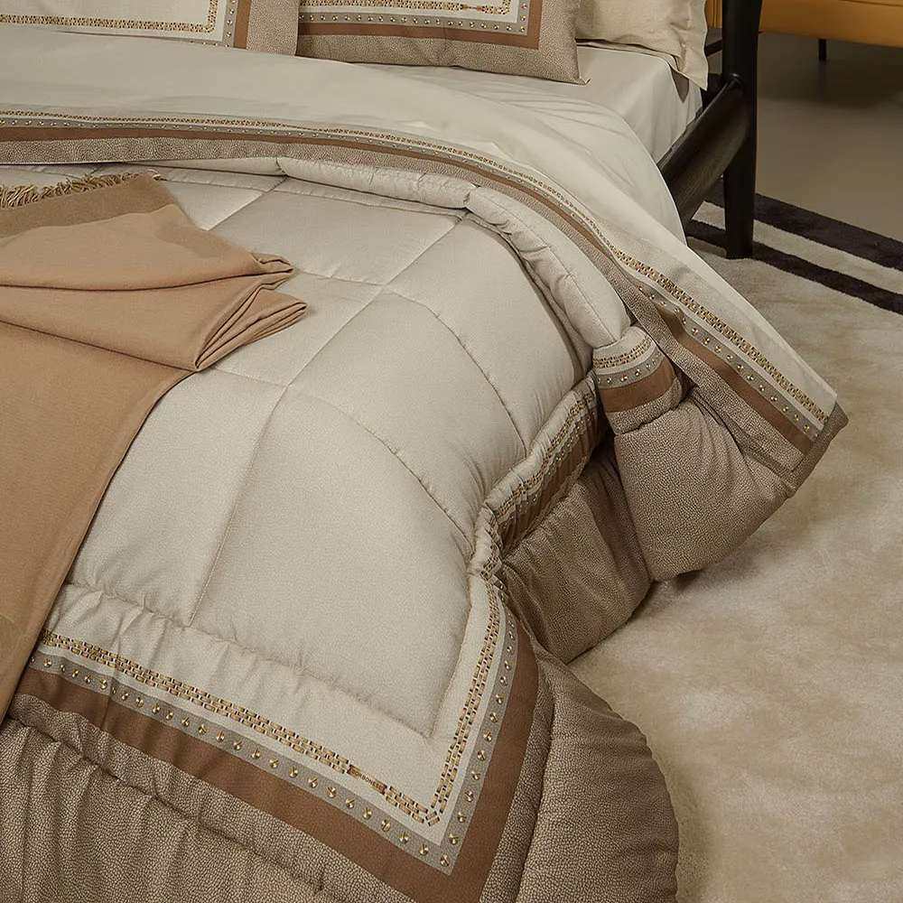 Trapunta invernale Borbonese Posh in raso di cotone per letto matrimoniale. Il piumone Posh è caratterizzato da una fantasia moderna in cui la tipica stampa Borbonese a occhio di pernice, nella tonalità beige, è incorniciata da una catenina dorata recante il logo Borbonese. La parte esterna riprende la stessa fantasia nella colorazione tortora