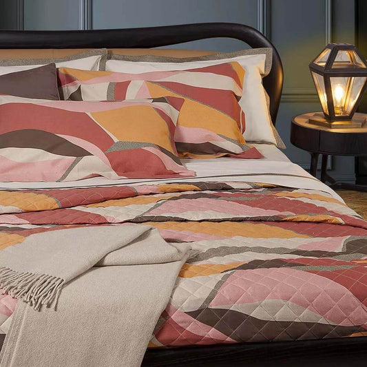 Trapuntino matrimoniale Wave Borbonese, in raso di puro cotone stampato. La trapunta primaverile Wave è caratterizzata da una fantasia moderna a onde, con colori vivaci e stampa a occhio di pernice. Colore marrone, arancio e rossiccio. Trapuntata a rombi e rifinita con angoli stondati.