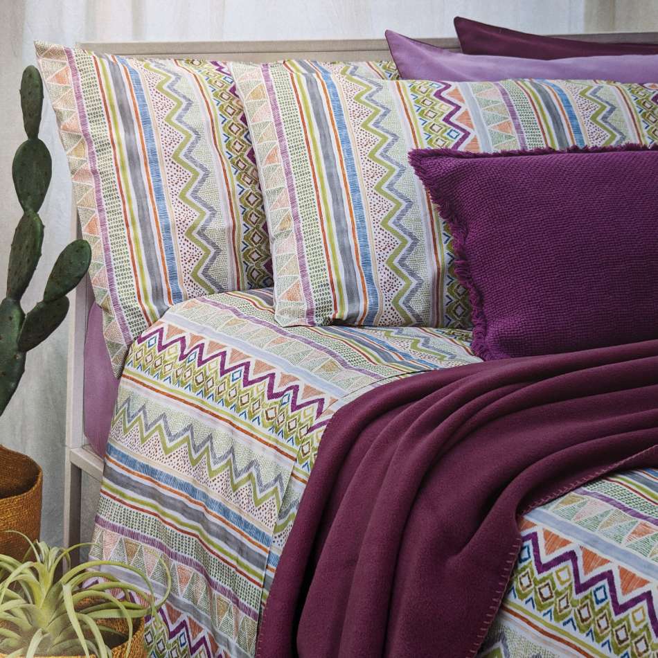 Completo lenzuola Fazzini Ande in percalle di puro cotone. Disponibile per letto singolo e piazza e mezza. Il completo lenzuola Ande è caratterizzato da un'allegra fantasia con righe di varie forme e colori. Variante di colore rosa giallo verde. La fantasia è presente sulle federe e sul lenzuolo di sopra. Il lenzuolo con angoli è in tinta unita color rosa.