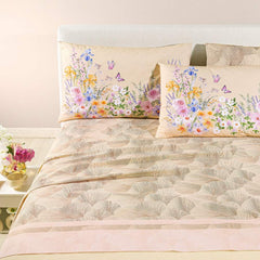 completo lenzuola caleffi yasmine. federe con fantasia a fiorellini arancio, rosa e blu. lenzuolo con foglie di ginkgo. variante naturale beige.
