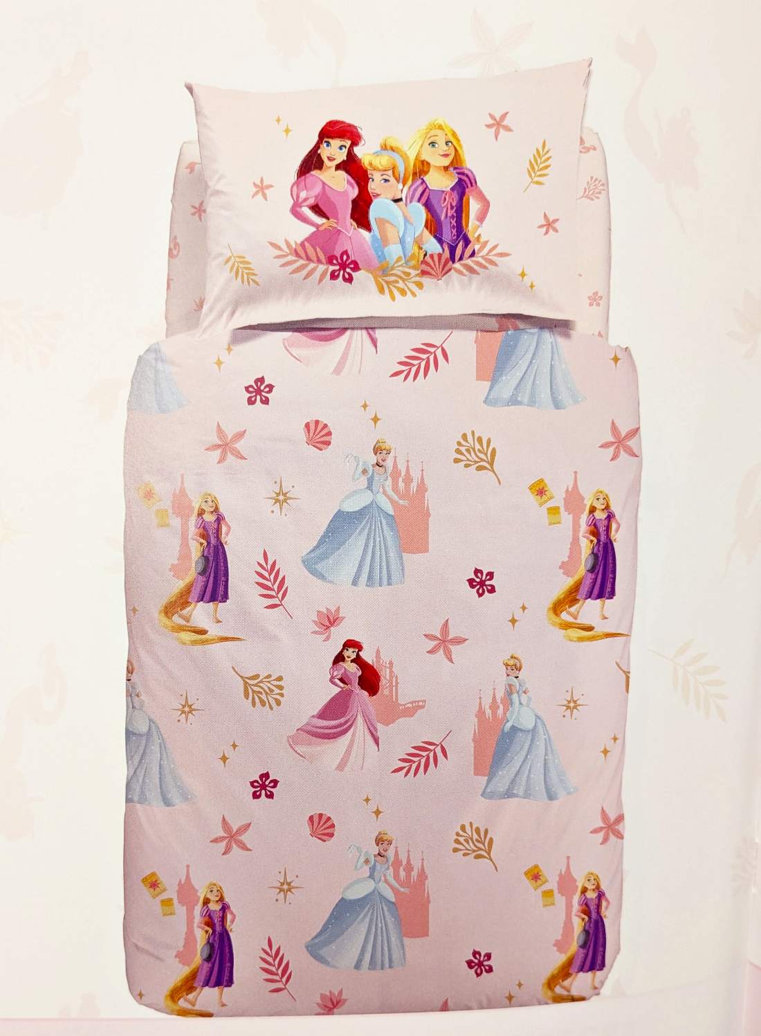 Copripiumino Magic Princess Caleffi Disney. Fantasia con le principesse Disney Cenerentola, Rapunzel, La Sirenetta Ariel, circondate da fiori su fondo rosa.