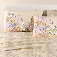 completo lenzuola caleffi yasmine. federe con fantasia a fiorellini arancio, rosa e blu. lenzuolo con foglie di ginkgo. variante naturale beige.