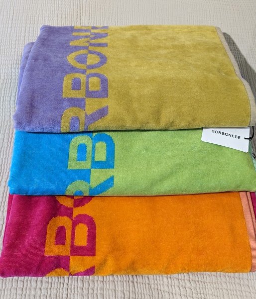 Telo mare Borbonese&nbsp;Trinidad, in spugna di puro cotone. Telo mare Borbonese in spugna di cotone stampata con logo Borbonese, con 3 abbinamenti di colore: fuxia/arancio, viola/ocra, turchese/verde. Spugna di cotone 380 g/mq. Misura 90x160 cm.