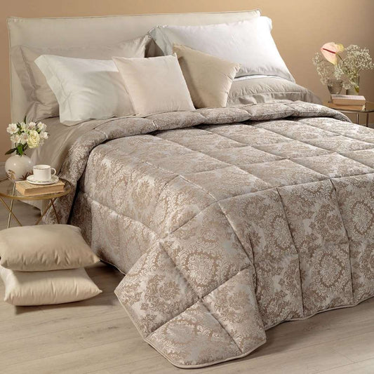 Trapunta invernale matrimoniale Caleffi Mida, in prezioso raso jacquard. Il piumone Mida presenta una fantasia dallo stile classico, nella variante di colore naturale tortora.