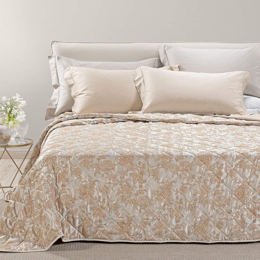 Trapuntino matrimoniale Caleffi Fioralba, in elegante raso jacquard.La trapunta primaverile Fioralba presenta una delicata fantasia floreale tono su tono. Colore tortora con venature bronzo/dorato.