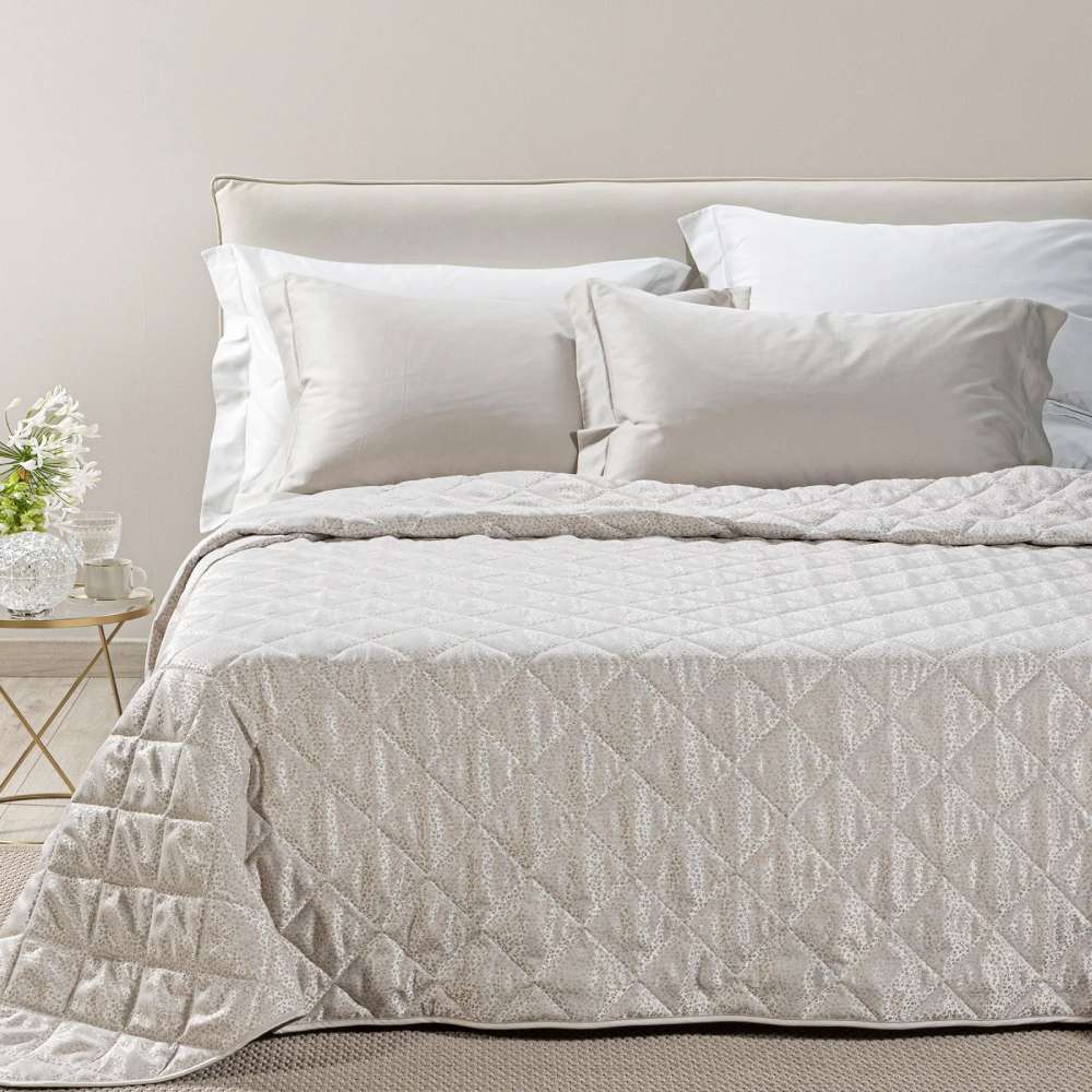Trapuntino matrimoniale Caleffi Perleè, in elegante raso jacquard.La trapunta primaverile Perleè è caratterizzata da una fantasia geometrica moderna a puntini, colore vaniglia