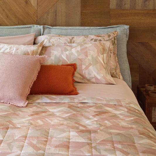 Trapunta primaverile matrimoniale Fazzini Symphonic, in percalle di puro cotone. Il trapuntino Symphonic presenta una moderna fantasia geometrica nel colore rosa. Il quilt è trapuntato a capo e rifinito a mano con due angoli sagomati che lo adattano perfettamente agli angoli del letto
