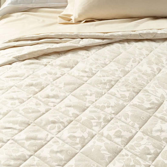 Trapunta primaverile matrimoniale Caleffi Floral in prezioso raso jacquard. Romantica e delicata fantasia floreale nella variante di colore avorio. Dettaglio fantasia.