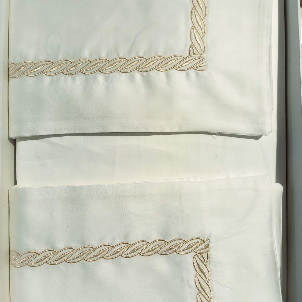 Completo lenzuola matrimoniale Caleffi Treccia, in raso di puro cotone. Il completo lenzuola Treccia è in tinta unita bianca, con elegante ricamo bianco a forma di treccia. Variante naturale con ricamo beige