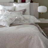 Copriletto estivo matrimoniale Leslie di Blumarine, in elegante raso jacquard. Romantica fantasia jacquard con linee sinuose che si intrecciano a formare delle rose, colore beige/tortora, con logo Blumarine in preziosi cristalli Swarovski. Coperta estiva