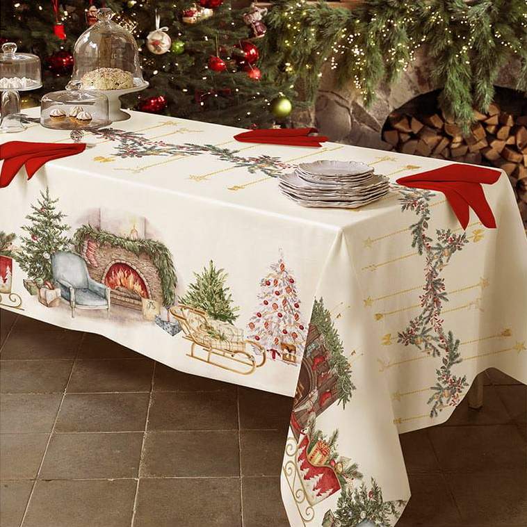 Tovaglia natalizia rettangolare Cozy di Tessitura Randi. Stampa digitale su puro cotone.  Fantasia su fondo avorio con elementi tipici del periodo natalizio come il camino accesso, l'albero di Natale, ghirlande e slitte con regali.