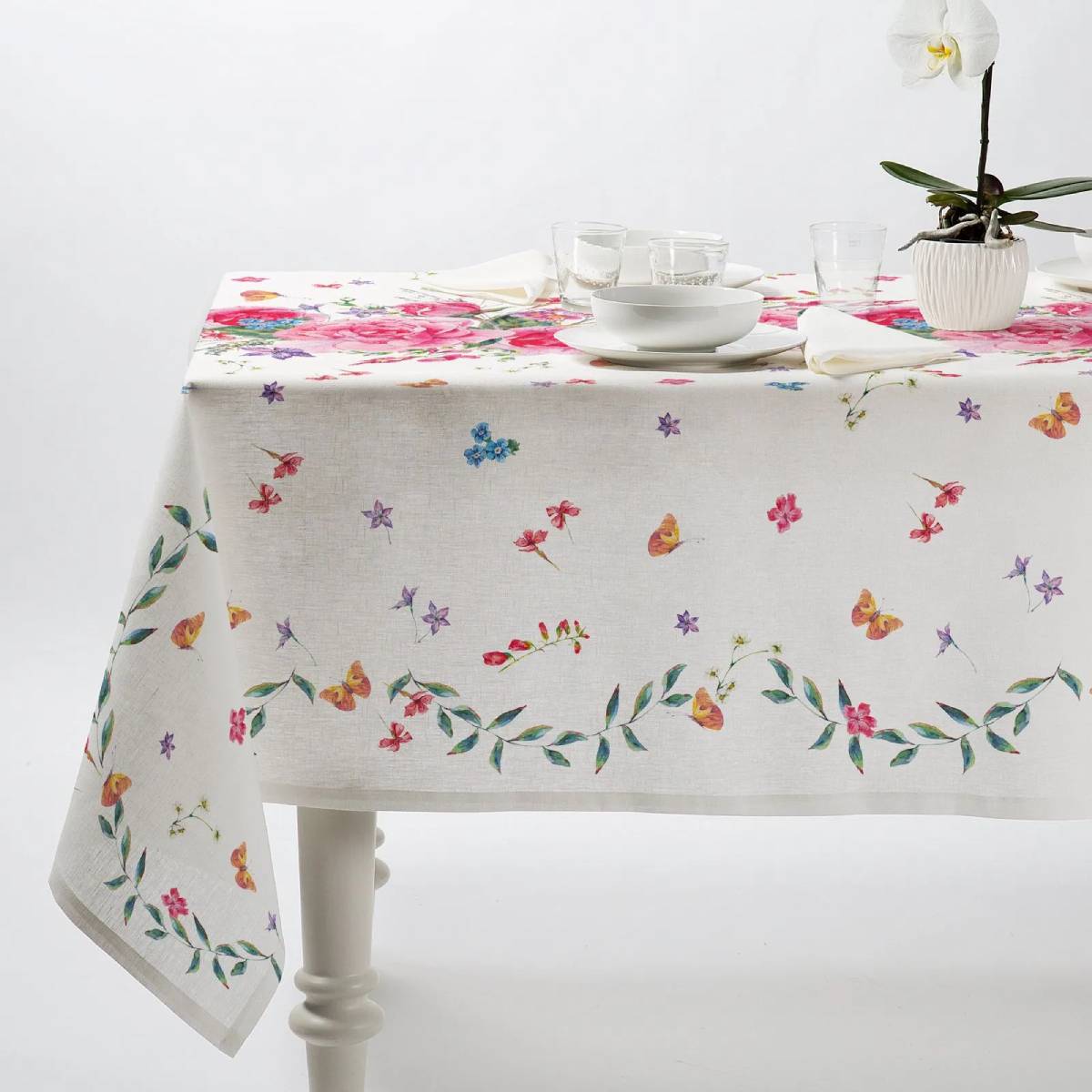 Tovaglia Caleffi Roseto in panama di puro cotone con stampa digitale. Fantasia con bouquet di rose sul lato superiore del tavolo, e fiorellini e farfalle sulla parte laterale. Fondo bianco.