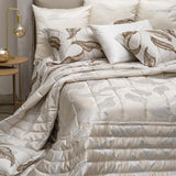 Trapuntino matrimoniale Luce di Blumarine, in elegante raso jacquard. Trapunta primaverile con elegante fantasia jacquard con foglie argentate che risaltano sul fondo tinta unita burro avorio. Copriletto trapuntato, quilt. Il ogo Blumarine è tinto in filo nella trama del tessuto.