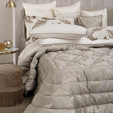 Trapuntino matrimoniale Luce di Blumarine, in elegante raso jacquard. Trapunta primaverile con elegante fantasia jacquard con foglie dorate che risaltano sul fondo tinta unita tortora. Copriletto trapuntato, quilt. Il ogo Blumarine è tinto in filo nella trama del tessuto.