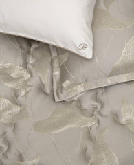 Trapuntino matrimoniale Luce di Blumarine, in elegante raso jacquard. Trapunta primaverile con elegante fantasia jacquard con foglie dorate che risaltano sul fondo tinta unita tortora. Copriletto trapuntato, quilt. Il ogo Blumarine è tinto in filo nella trama del tessuto.